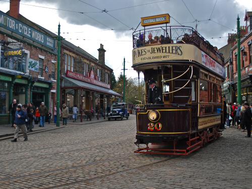 1800s tram and conductor making its way through one of the historic streets at Beamish Open Air Museum