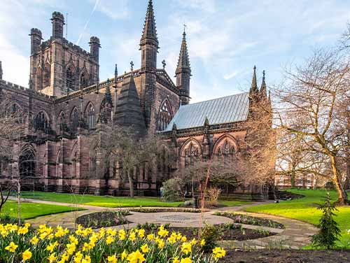 The exterior of Chester cathedral surrounded by green grass and trees