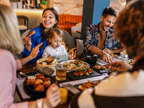 Family smiling and eating round a restaurant table