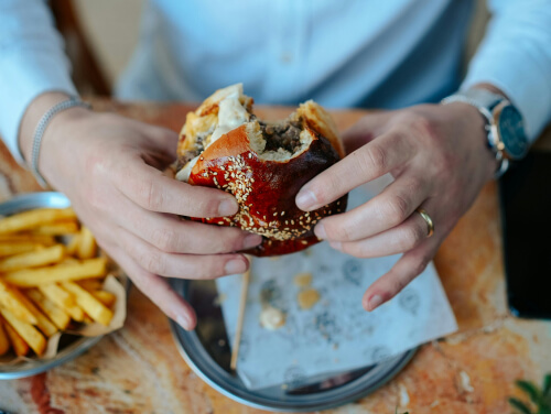 An image of a person's hands holding a burger.