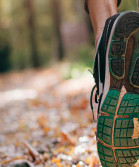 A close-up of the sole of a trainer of someone running in the woods