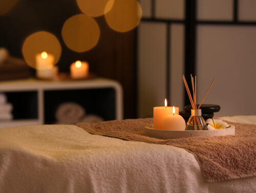 A tray of candles and a reed diffuser on a spa bed.